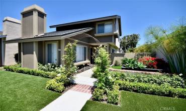 The front yard showcases a beautifully manicured landscape with freshly planted greenery and vibrant flowers, enhancing the curb appeal of the home.