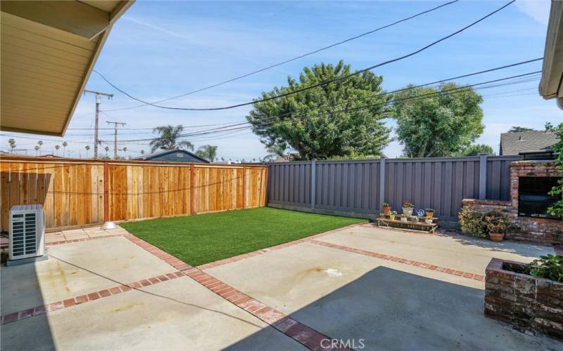 Spacious backyard with large patio and energy-efficient turf. Brick BBQ area.