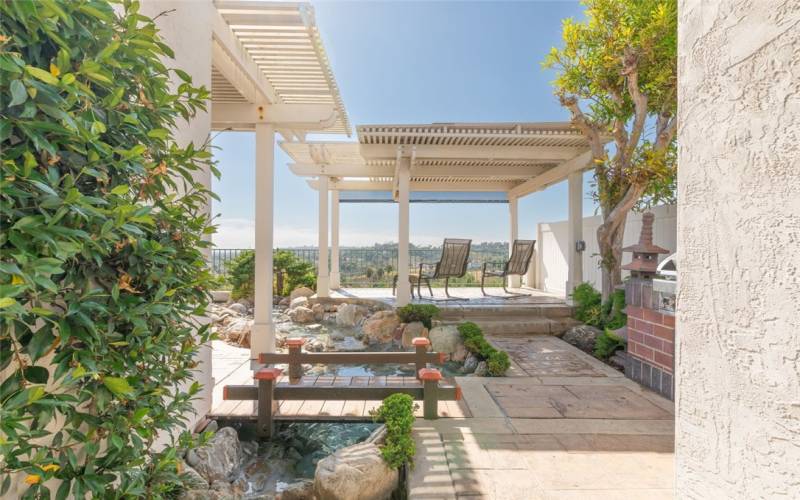 Patio Area w/ Stamped Concrete, Lush Plants, Koi Pond (New Motor), New BBQ & Raised & Shaded Sitting Area For Ultimate Views.