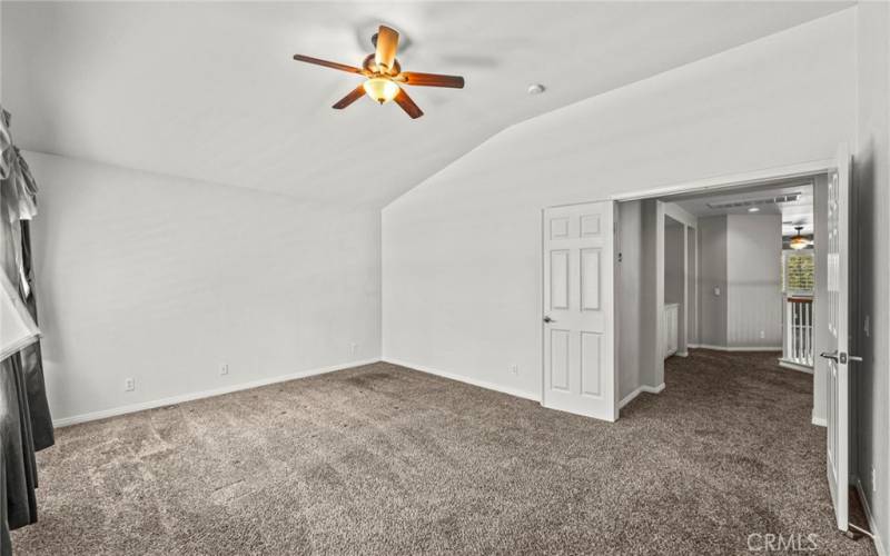 The primary bedroom, featuring luxurious wall-to-wall carpeting that adds warmth and elegance to the space. This inviting retreat is enhanced by a stylish ceiling fan.