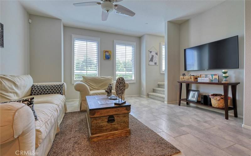 Living room featuring upgraded tiles, ceiling fan and plantation shutters