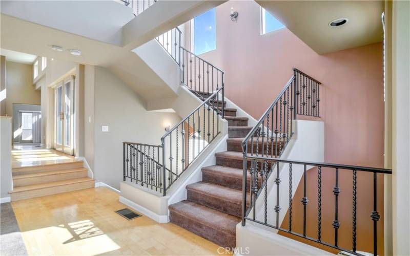 Beautiful staircase with wroght iron railing, impressive windows and soaring ceilings