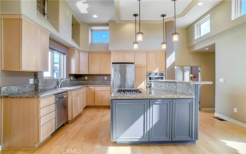 Entertainer's kitchen with center island with countertop seating, granite counters, ample cabinetry, stainless appliances, soraring ceilings, hardwood floors and more.