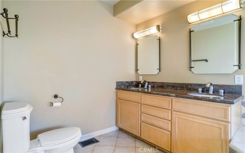 Primary bath with custom lighting, granite counters, maple cabinetry, dual vanities and more.