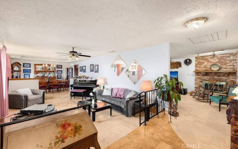 Primary Home - Looking From the Front Entry into the Step Down Living Room, Formal Dining Room and Family Room with Brick Fireplace