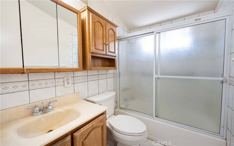 Hallway full bath with tub/shower combo, tile shower, tiled wall accents & a tile floor