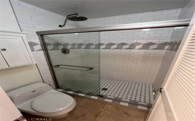 The primary suite's large, tiled, walk-in shower with room for a chair.