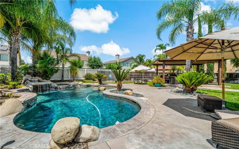 Pebbletech pool adorned with a variety of palm trees.