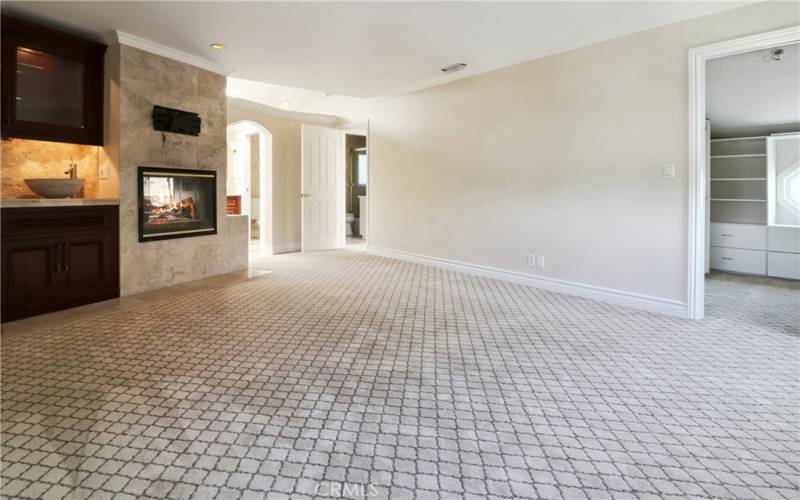 Alternative angle from inside primary suite where in room sink, fireplace and walk in closet.