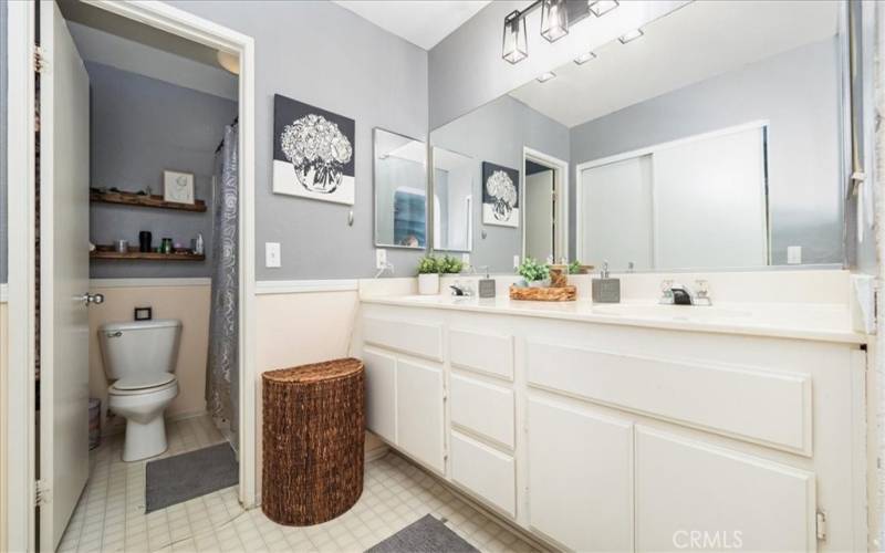 Primary bathroom with double sinks and separate area for shower and toilet.