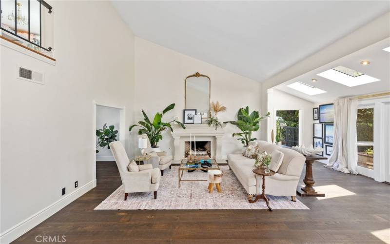 The formal living room with soaring vaulted ceilings, a romantic custom fireplace, and wide plank French oak floors.