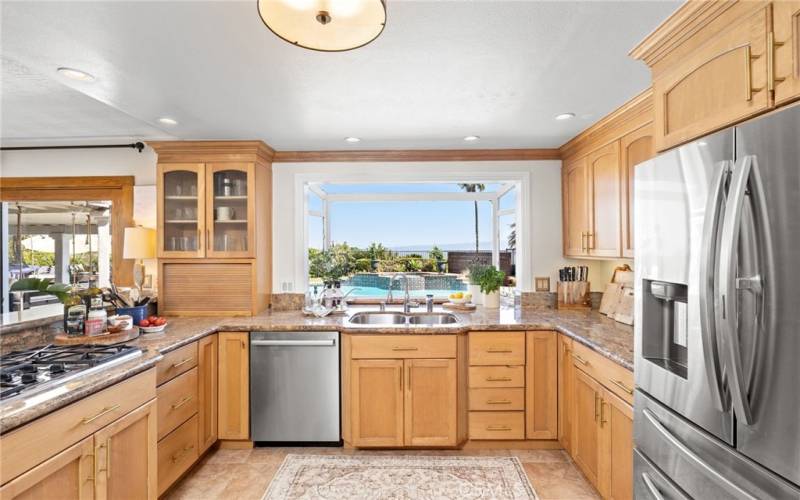 Bright eat-in kitchen, featuring stainless steel appliances and custom cabinets, flows seamlessly into the formal dining room and  family room.