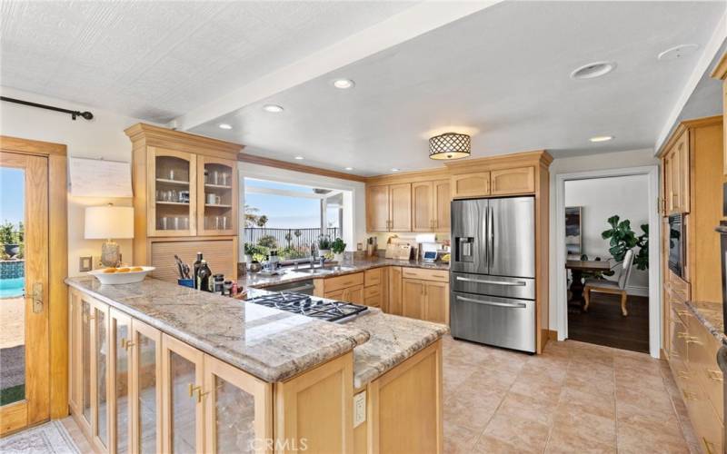 Bright eat-in kitchen, featuring stainless steel appliances and custom cabinets, flows seamlessly into the formal dining room and  family room.