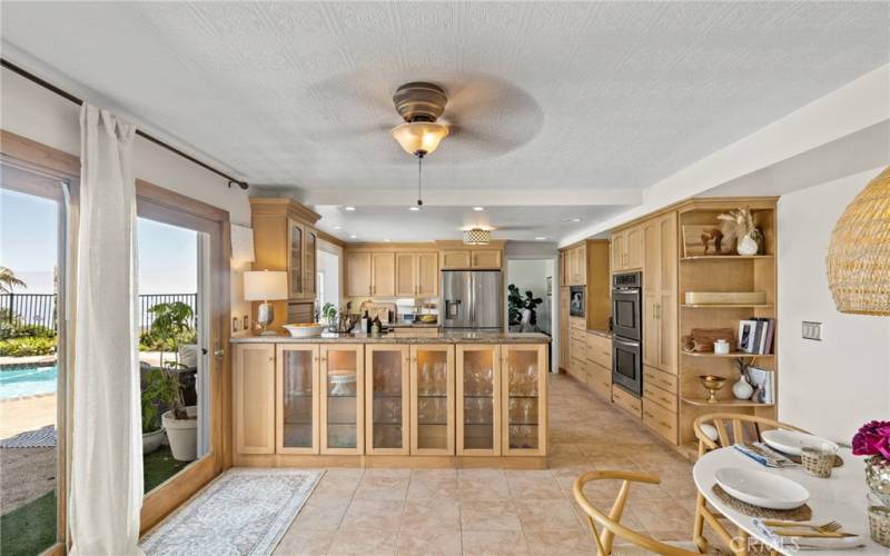 Bright eat-in kitchen, featuring stainless steel appliances and custom cabinets, flows seamlessly into the formal dining room and  family room.