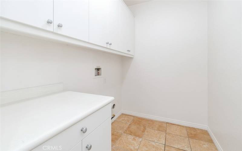 The laundry room offers plenty of cabinet storage space and a counter.