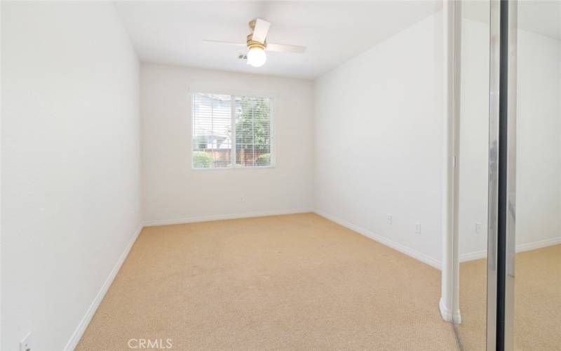 Bedroom 1 offers a mirrored closet door, a ceiling fan with light and carpet flooring.