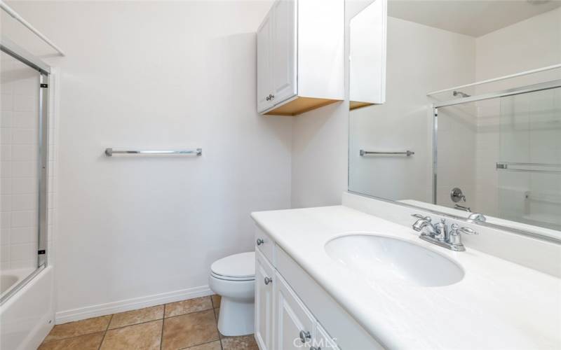 Bathroom 1 offers a shower/tub combo with a glass door. There is a cabinet above the toilet for added storage.