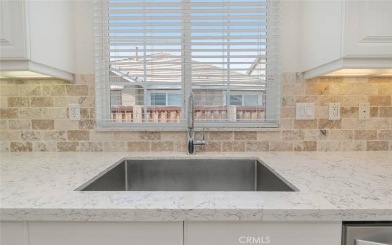 The stainless steel sink has a window above that provides a view of the backyard.