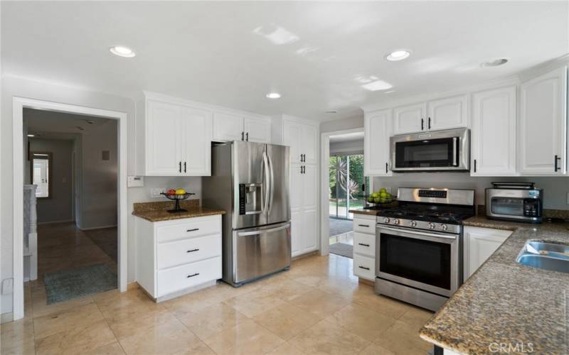  The bright and upgraded kitchen offers granite counters, stainless steel appliances, recessed lighting, pantry space, and newly lacquer-finished kitchen cabinets.
