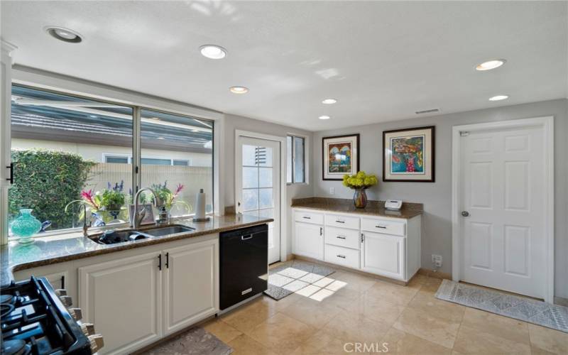 The bright and upgraded kitchen offers granite counters, stainless steel appliances, recessed lighting, pantry space, and newly lacquer-finished kitchen cabinets.