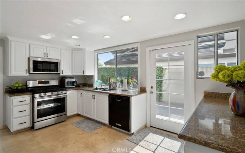 The bright and upgraded kitchen offers granite counters, stainless steel appliances, recessed lighting, pantry space, and newly lacquer-finished cabinets.