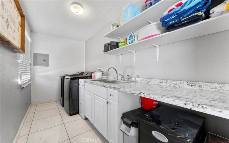 Indoor lower level laundry with room to fold and extra sink.