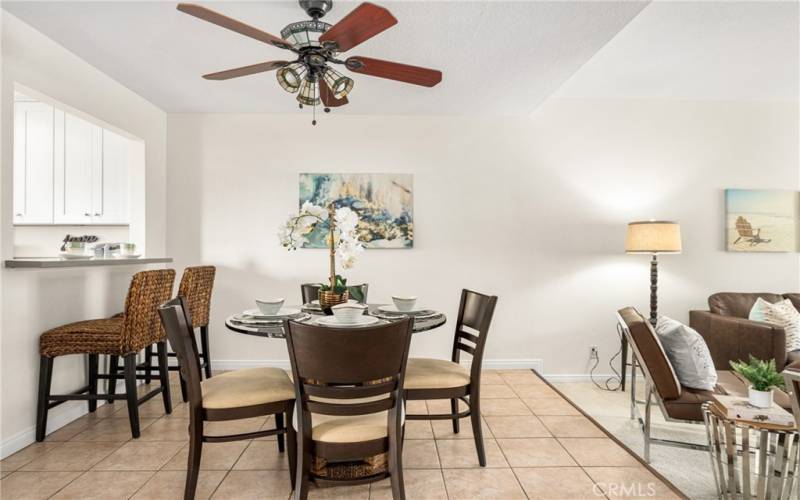 Dining area with ceiling fan, and breakfast bar with quartz counters opening to kitchen.