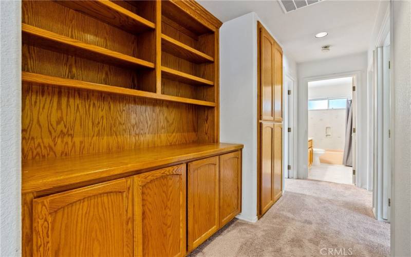 Aisle to bedrooms with inbuilt shelves and linen closet