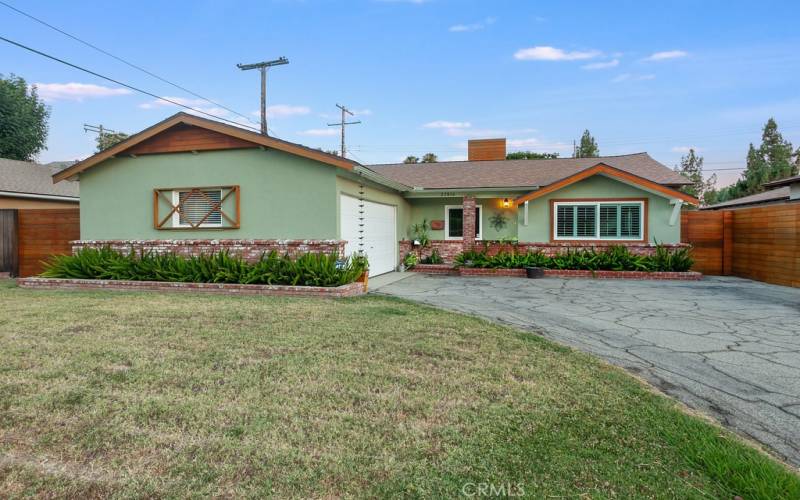 The front lawn, colorful custom raised brick planters and covered custom brick entry enhance its eye-catching curb appeal.  The custom wood front door with glass, decorative wrought iron insert and window that opens, sweeps open to a bright and flowing floor plan.