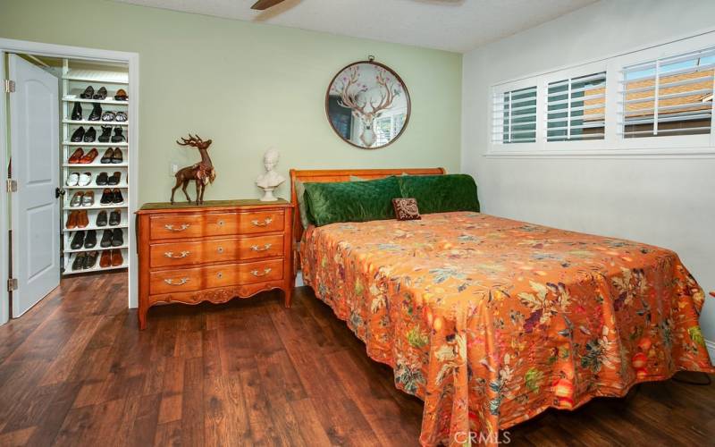 The primary bedroom is drenched in natural light and is enriched with newer plantation shutters, lighted ceiling fan, large walk-in closet with shoe and sweater organizers, an additional standard closet and newer high-end wood laminate floors.