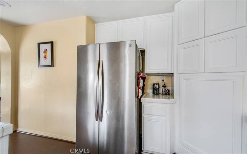 Side by side door refrigerator at entrance of kitchen., including storage space.