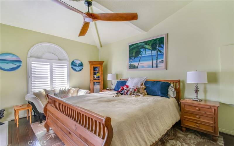 Primary bedroom, including vaulted ceiling, ceiling fan, dual pane windows and shutters and padded laminate flooring throughout.