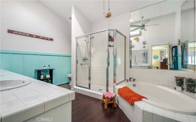 Huge primary bathroom including padded laminate flooring throughout, walk in shower, huge soaking tub, vaulted ceiling, ceiling fan and large mirror.