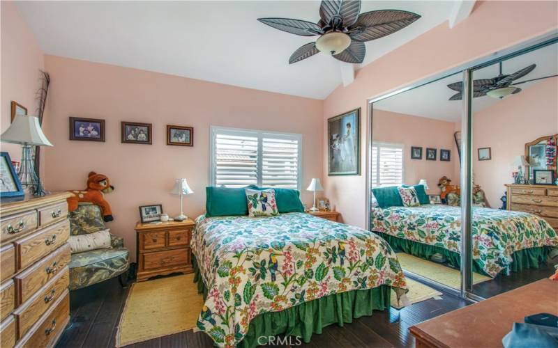 Second bedroom with large mirror closet sliders, dual pane window with shutter, ceiling fan and padded laminate flooring throughout.