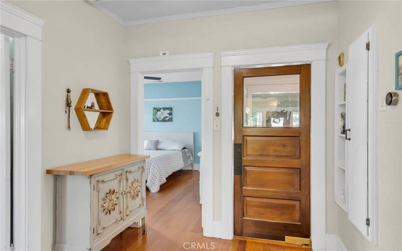 Laundry room area with original swinging door to formmal dining room, and view into the primary bedroom.