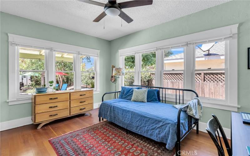 Bedroom #2 overlooking the backyard with lots of natural light, brand new window blinds, ceiling fan, and hardwood flooring.