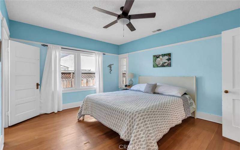 Primary bedroom with hardwood floors, ceiling fan, and en suite half bath.