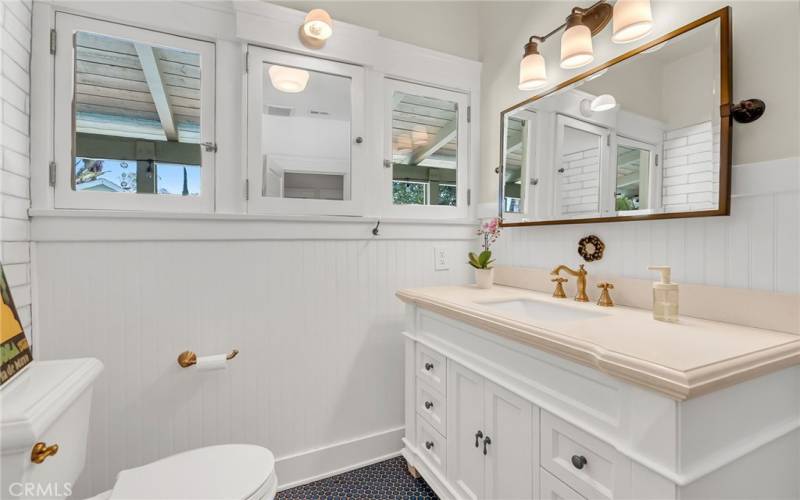 Remodeled hallway bathroom with tile floor and shower in tub.