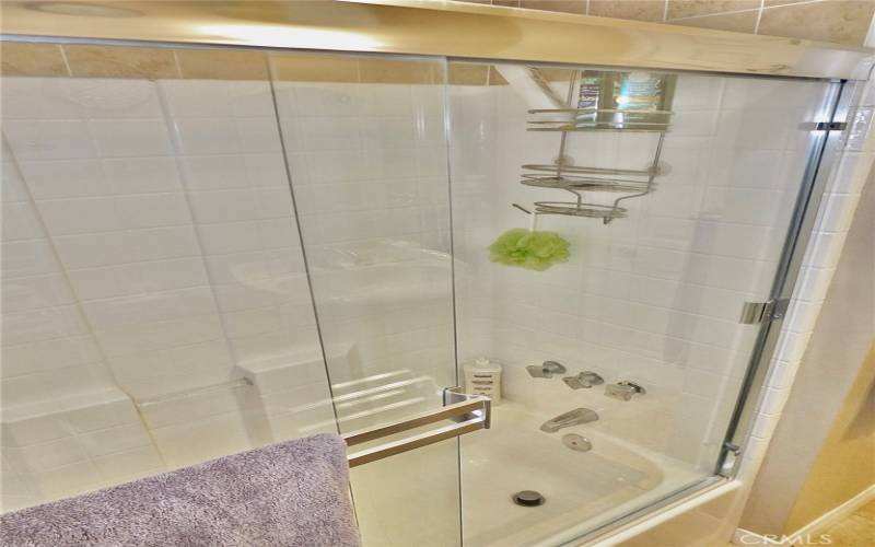 Experience the pristine elegance of a flawlessly clean, tiled tub and shower, beautifully complemented by sleek glass sliding enclosure doors.sliding enclosure doors.