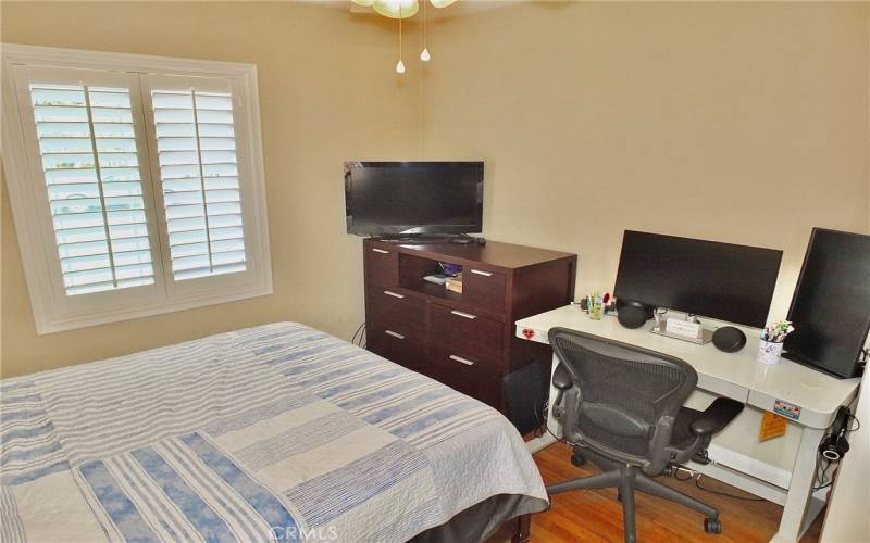 The second bedroom boasts beautiful wood flooring and a shuttered windows