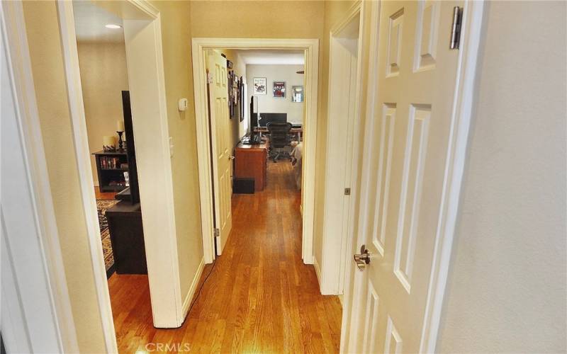 Hallway with beautiful wood flooring leading to all 3 bedrooms and linen closet