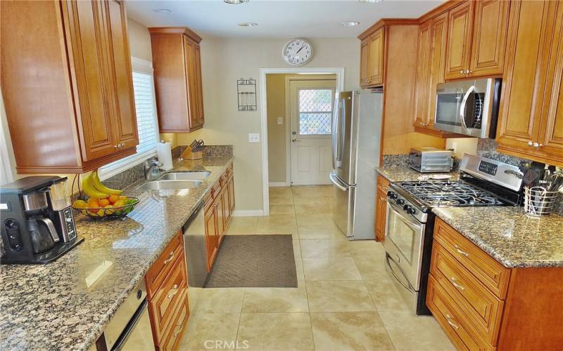 Fabulous Kitchen view with stainless steel appliances including microwave and wine refrigerator, trash compactor granite countertops, recessed lighting in the ceiling and lighting underneath top cabinets and tile flooring.