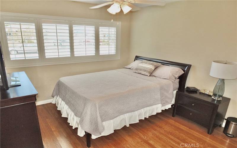 Another view of the front bedroom features stunning wood flooring, a ceiling fan with an integrated light, and a spacious mirrored wardrobe closet.