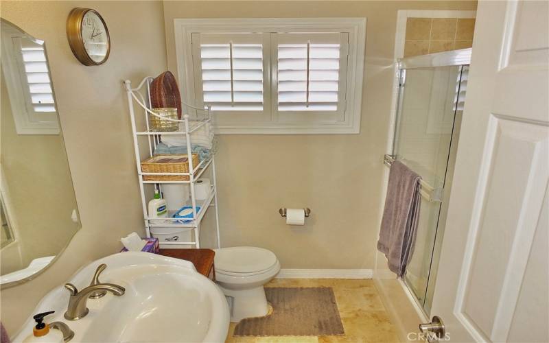 Step into the beautifully remodeled hallway bathroom, featuring elegant tile flooring and charming shutters on the window, adding both style and privacy to this serene space.