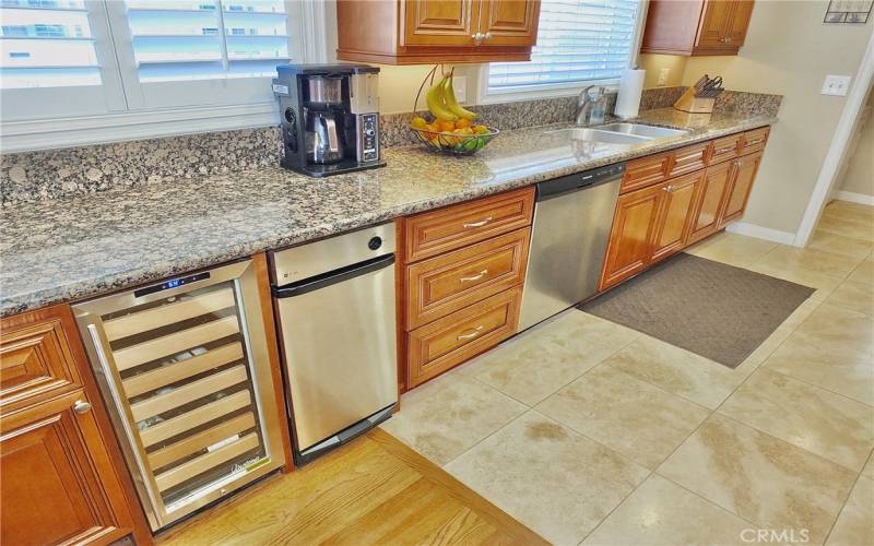 Beautiful wood flooring seamlessly transitions into elegant tile flooring in the kitchen.