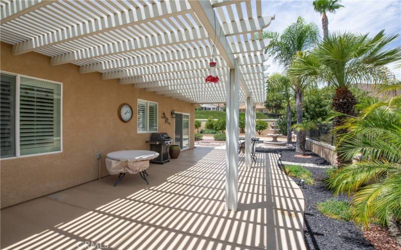 Wide golf course view patio with Alumawood cover, lush gardens and fountain.