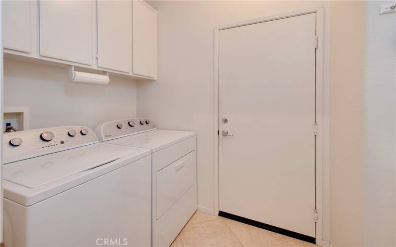 The laundry room has plenty of cabinets on both sides and a folding table.