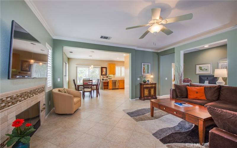 Wow! View Living/Great room with tile floors, custom tiles fireplace, custom paint, crown molding, ceiling fan, plantation shutters and built-in shelves and cabinet.