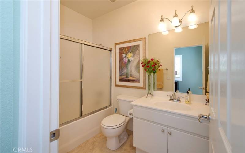 The hall/guest bath has an enclosed tub with shower over and tile floor.