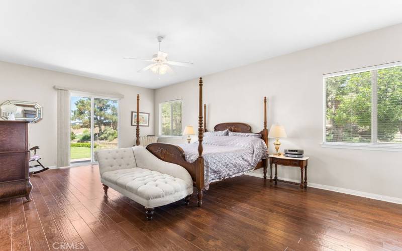 Primary bedroom with wood floors with sliders to backyard and spa.